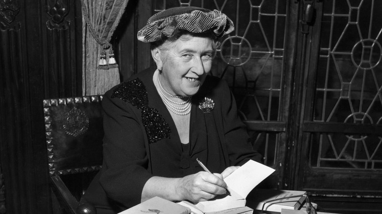 Agatha Christie smiling at writing desk