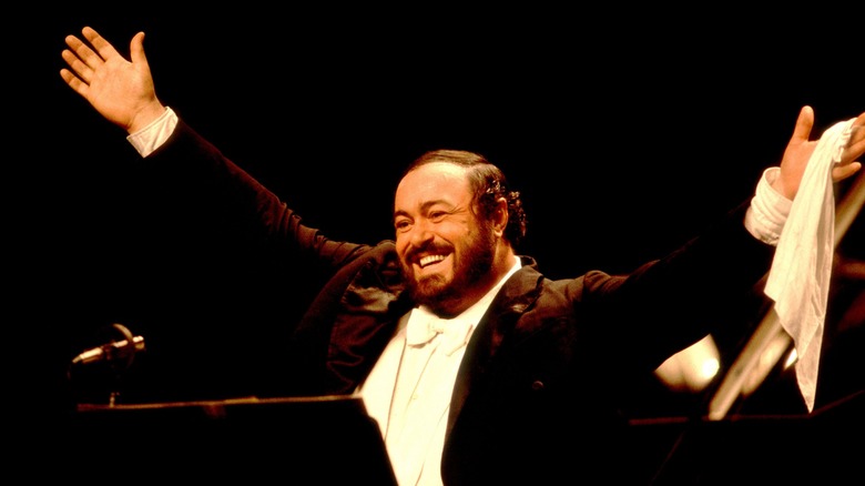 Luciano Pavarotti smiling onstage arms raised