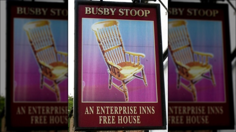 Sign for Busby Stoop inn and pub featuring chair.