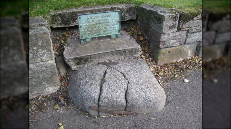 Forres witches stone with weathered copper sign.