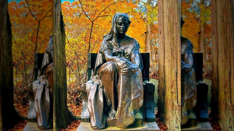 Bronze Lady statue in Sleepy Hollow Cemetery, orange and yellow fall leaves in background.