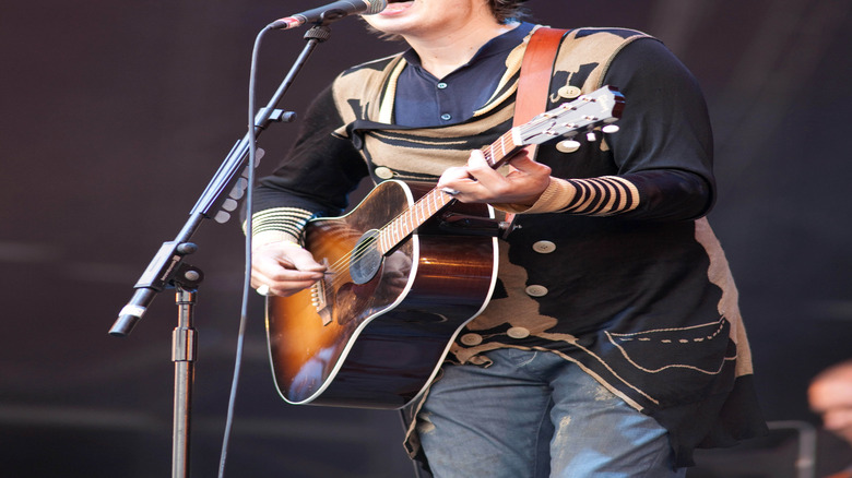 Pete Doherty playing guitar and singing on stage at Glastonbury in 2009