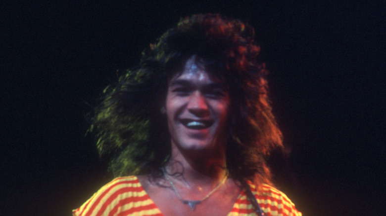 eddie van halen smiling while playing in yellow and red jumpsuit