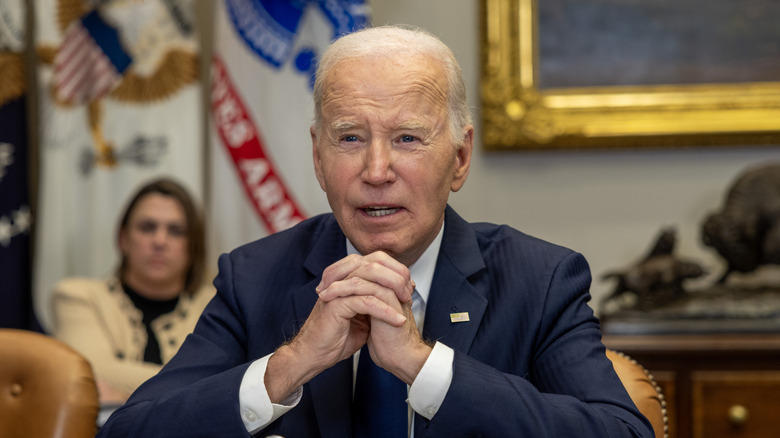 Joe Biden sitting down, speaking, with his hands laced together