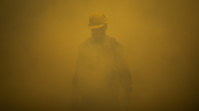 firefighter walking through smoke orange light