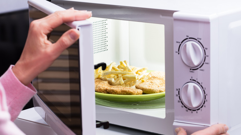 hands opening microwave oven door