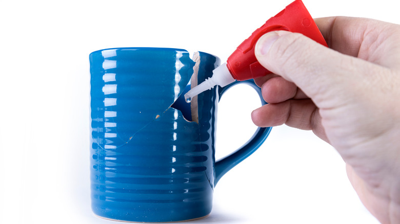 hand gluing broken blue mug