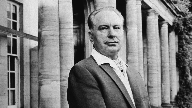 Suited L. Ron Hubbard standing in front of fancy building