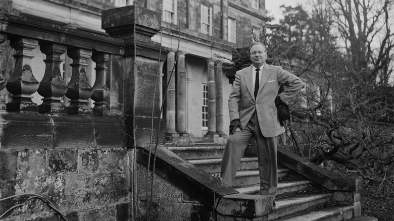 L. Ron Hubbard smiling standing outside house in suit