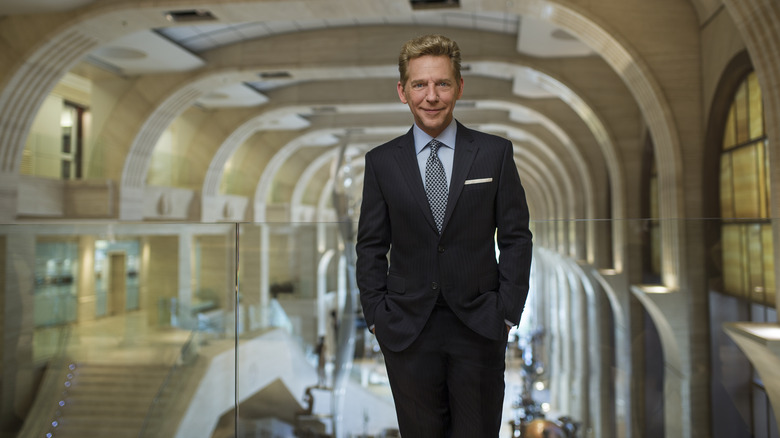 Suited smiling David Miscavige in museum-like building