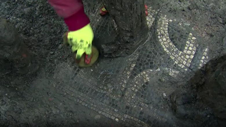 An archeologist brushes mud off the Roman mosaic