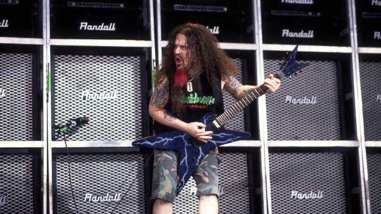 "Dimebag" Darrell Abbott plays guitar on stage in front of a wall of speakers