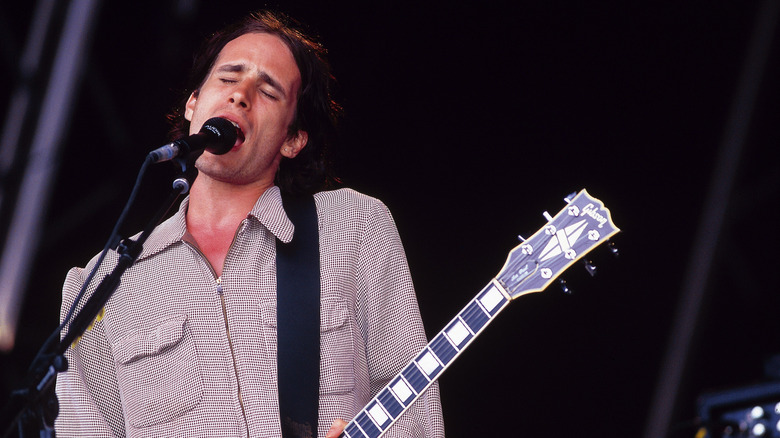 Jeff Buckley sings on stage with a guitar in his hands