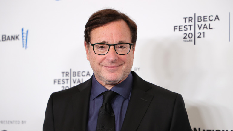 Bob Saget smiling glasses dark suit and tie at event