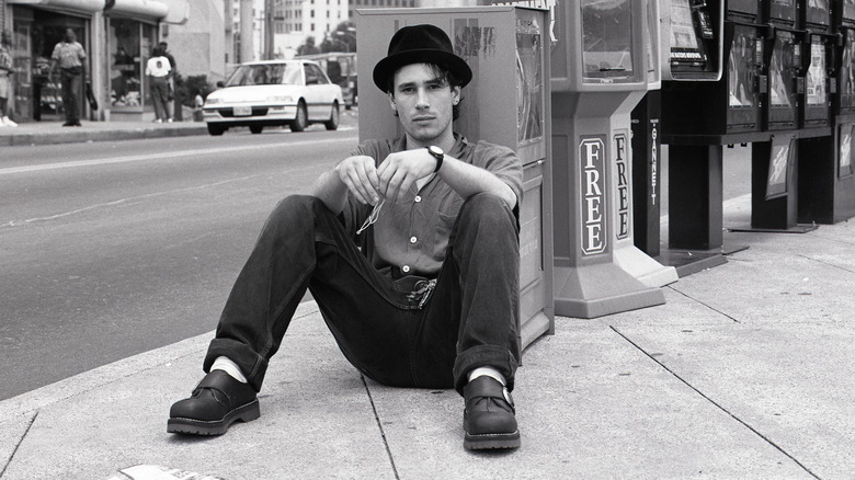 Jeff Buckley wearing a black hat sat on a street corner