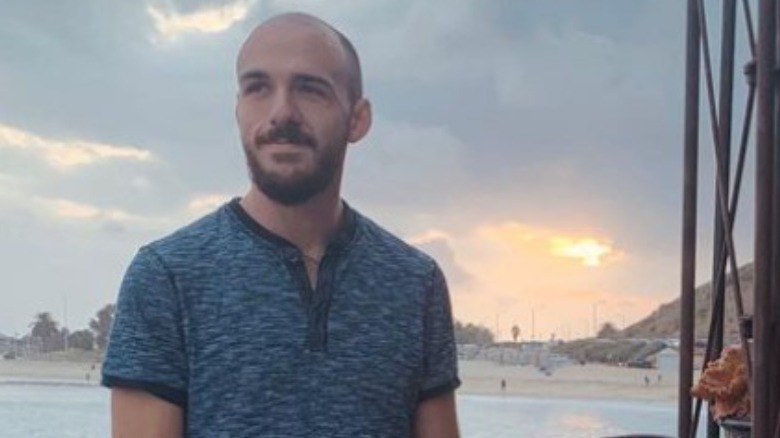 Brian Laundrie smiling in front of an ocean sunset