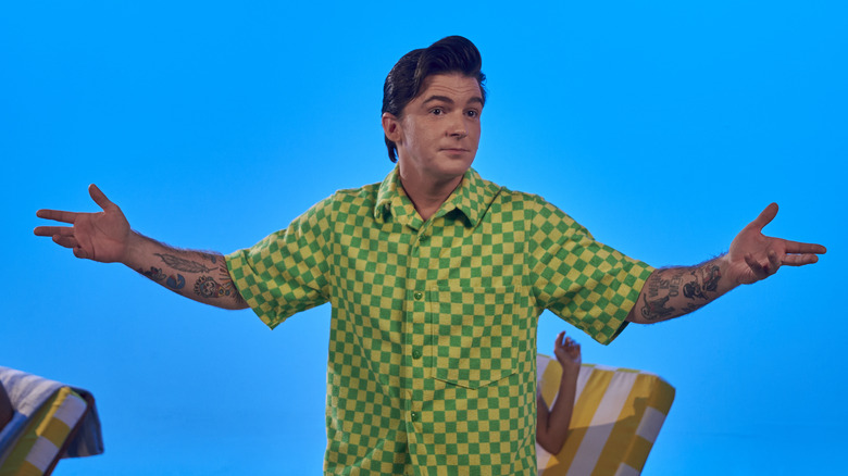 Drake Bell wearing a green shirt against a blue backdrop