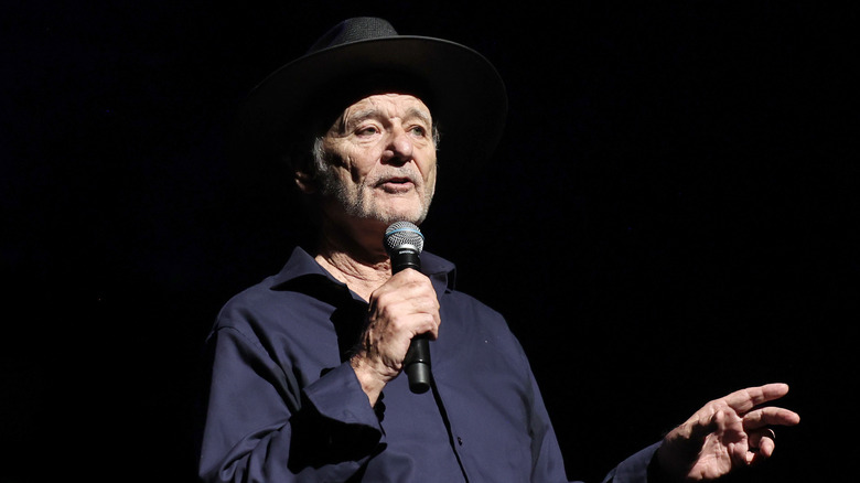 Bill Murray fedora holding microphone speaking on stage