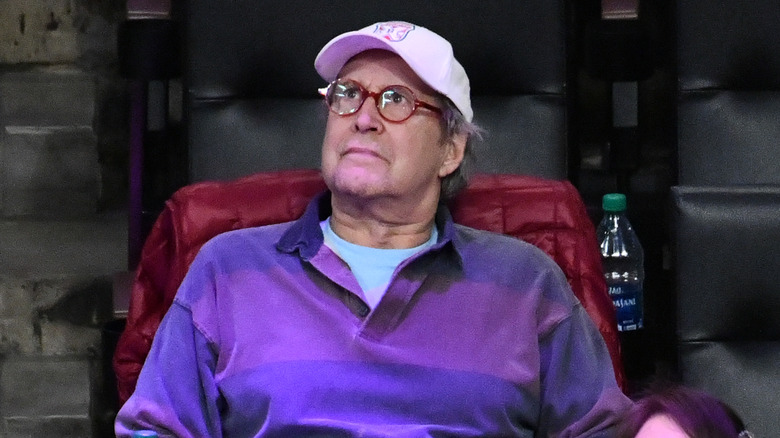 Chevy Chase purple shirt white cap looking up