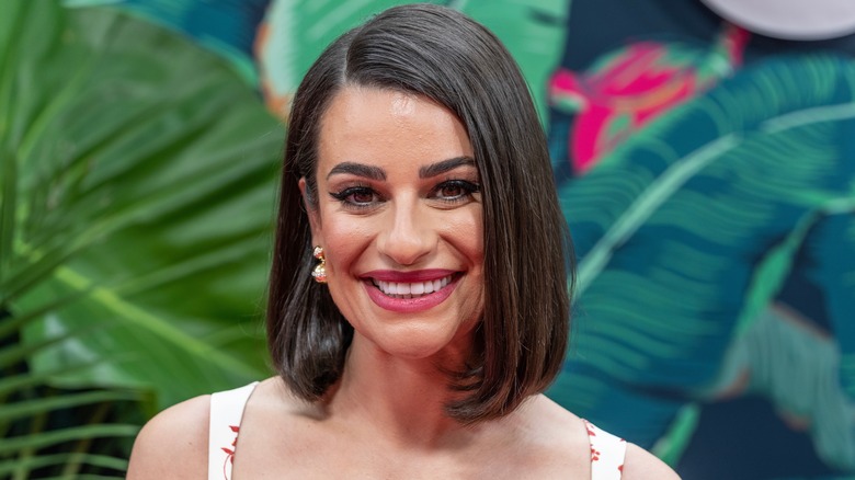 Lea Michele smiling with foliage in background