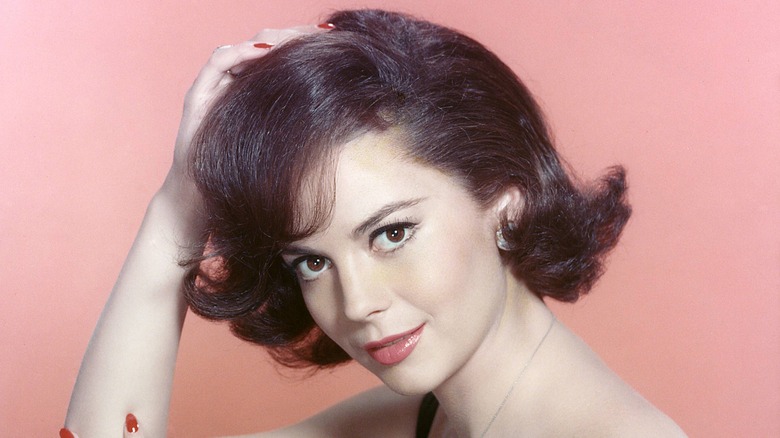 Natalie Wood smiling holding hair pink background