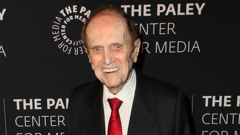 Bob Newhart smiling black suit red tie at event