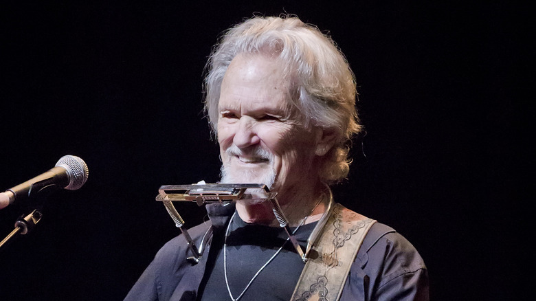 Kris Kristofferson smiling harmonica on stage