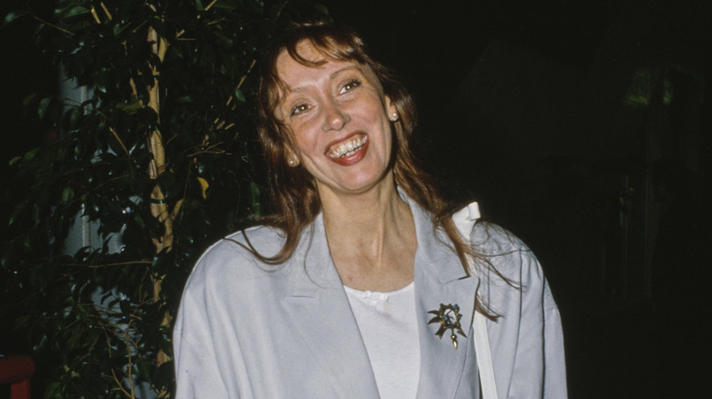 Shelley Duvall smiling wearing gold pin