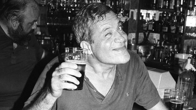 Oliver Reed holding pint smiling 1984