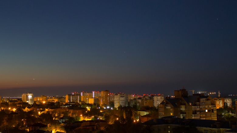 Cityscape at dawn with planets lined up in the sky.