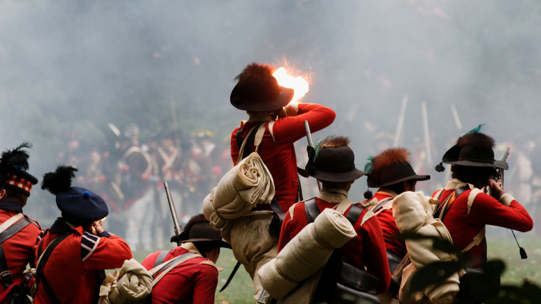 Reenactors dressed as British troops fire on Rebels