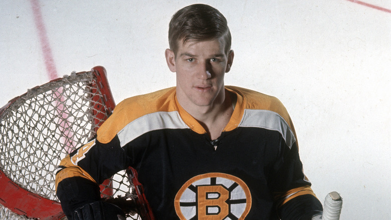 Bobby Orr leans on hockey net with stick