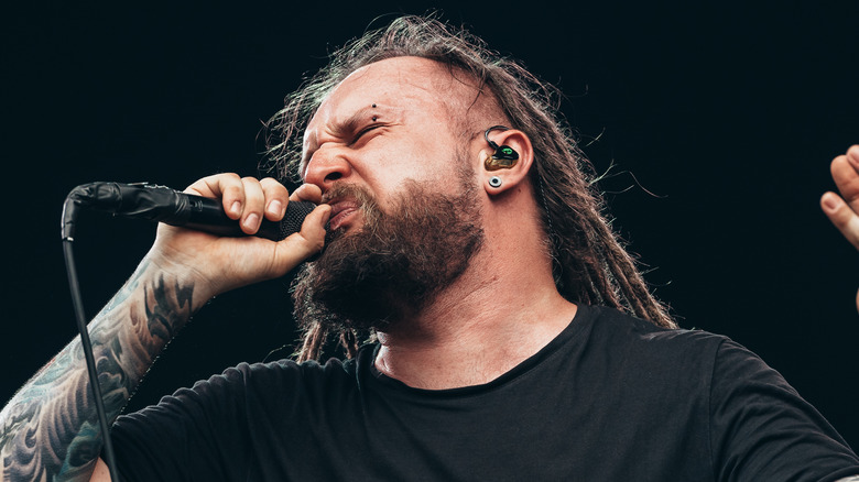 Decapitated singer Rafał Piotrowski rocking out on stage holding a microphone