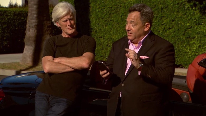 Keith Morrison leaning on a car outside with man in suit