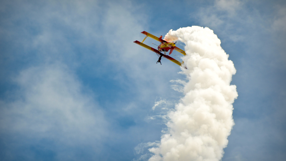 Biplane turning a loop with a white jet trail