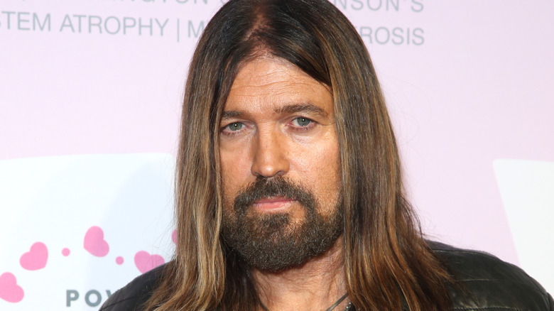 Billy Ray Cyrus with long hair and a beard looking sad