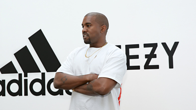 Kanye West posing with Adidas and Yeezy logos