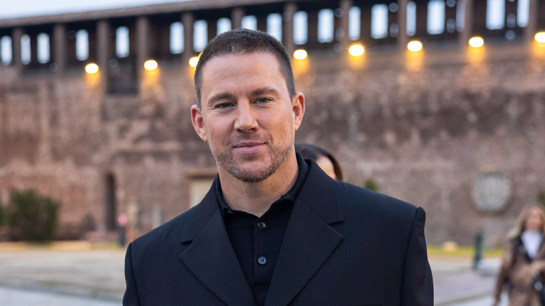 Channing Tatum in a dark suit smiling outside