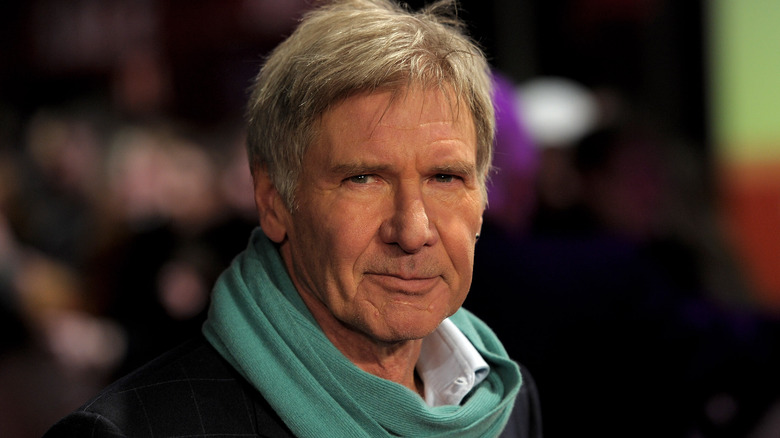 Harrison Ford wearing a scarf on a red carpet