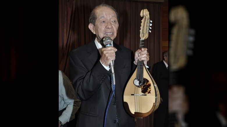 Shi Wen-Long talking and holding an instrument