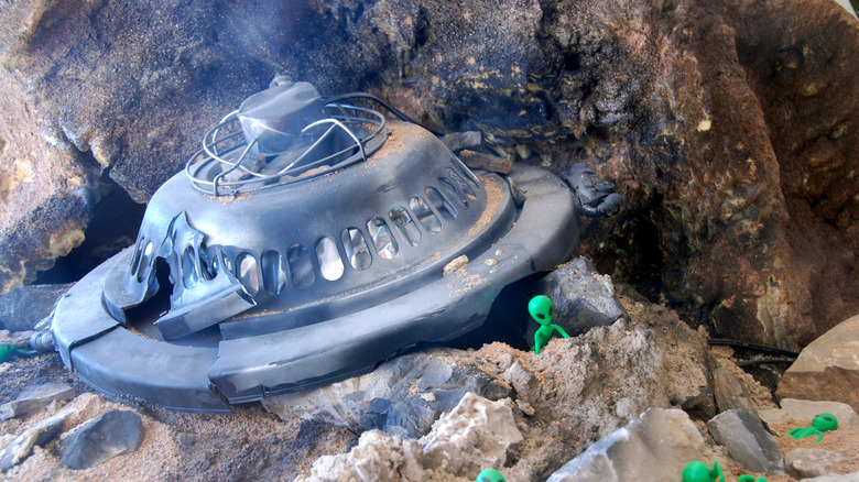 Model of crashed UFO surrounded by green aliens