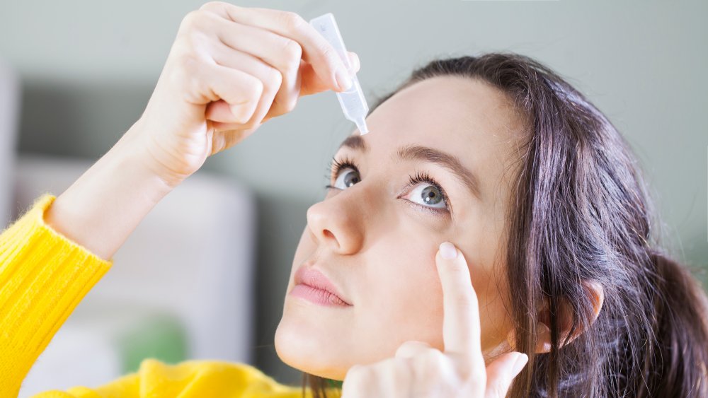 Young woman uses eye drops for eye treatment.