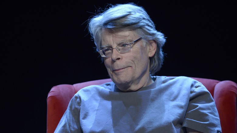 Stephen King on red chair under blue light