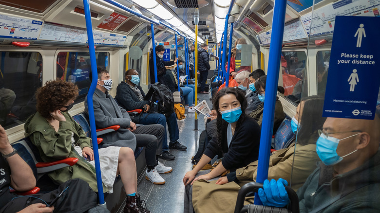 Masked London passengers w/social distancing sign