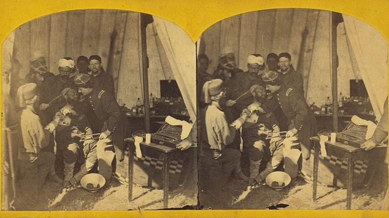 Men operating on soldier in tent