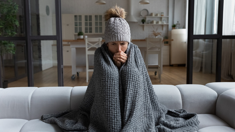 woman sitting on a couch with a blanket and hat on