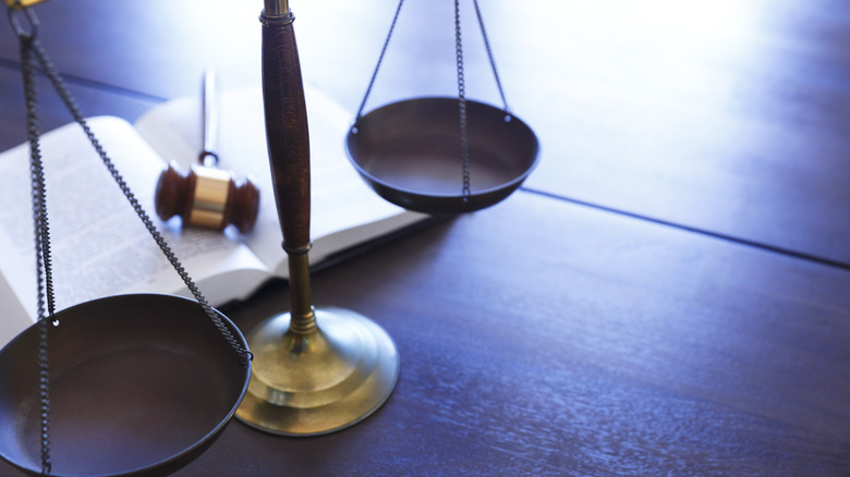 legal scales on desk with book and gavel behind