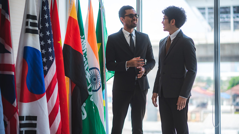 two diplomats talking with flags in foreground