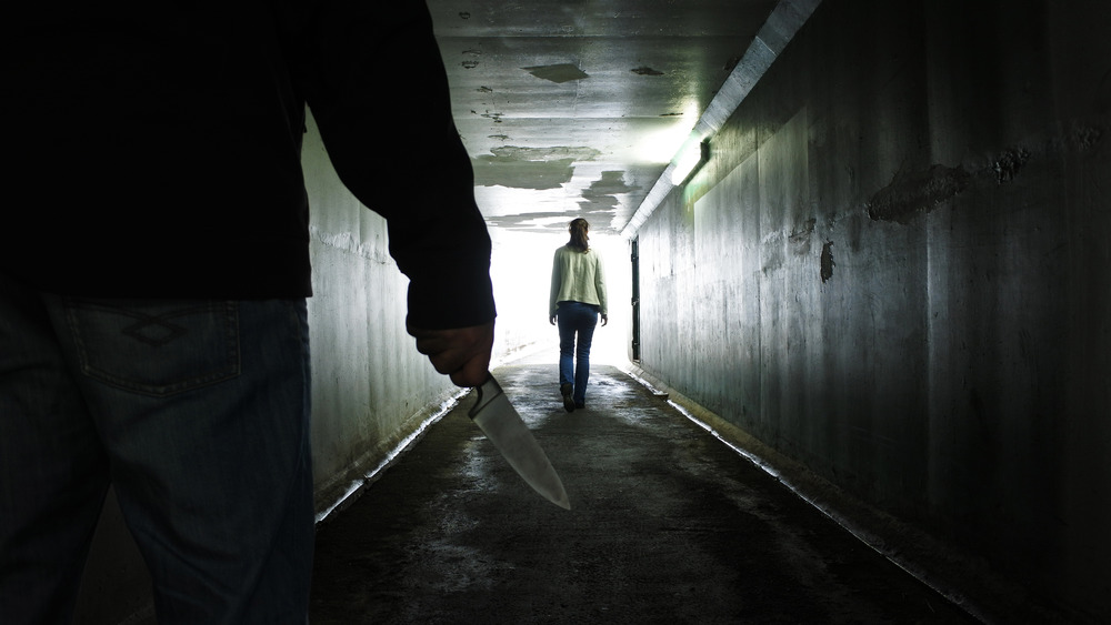 man following woman with knife