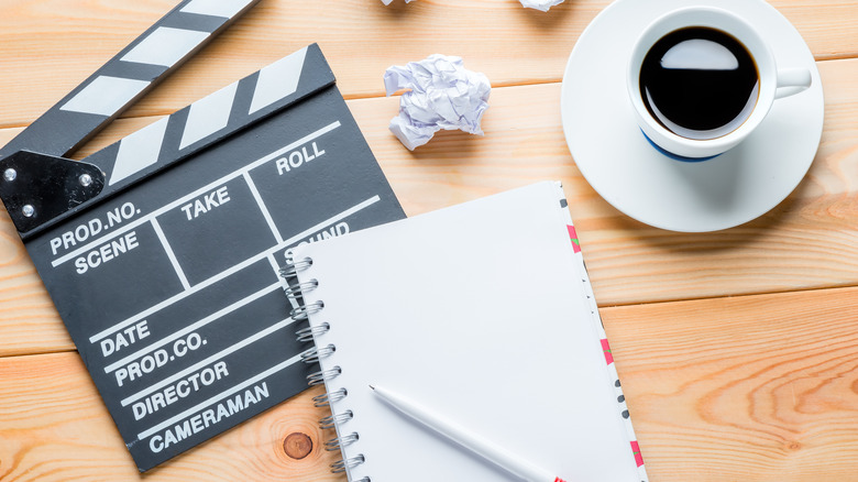 notebook, clapboard, and cup of coffee on table